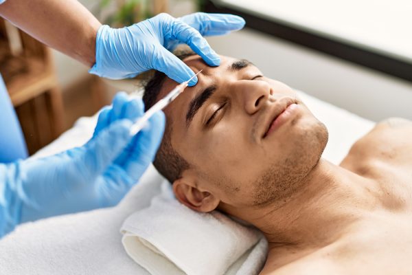 Doctor injecting botox on man face for anti aging treatment at the clinic.